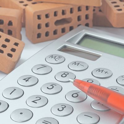 En lommeregner ligger på et bord blandt mursten