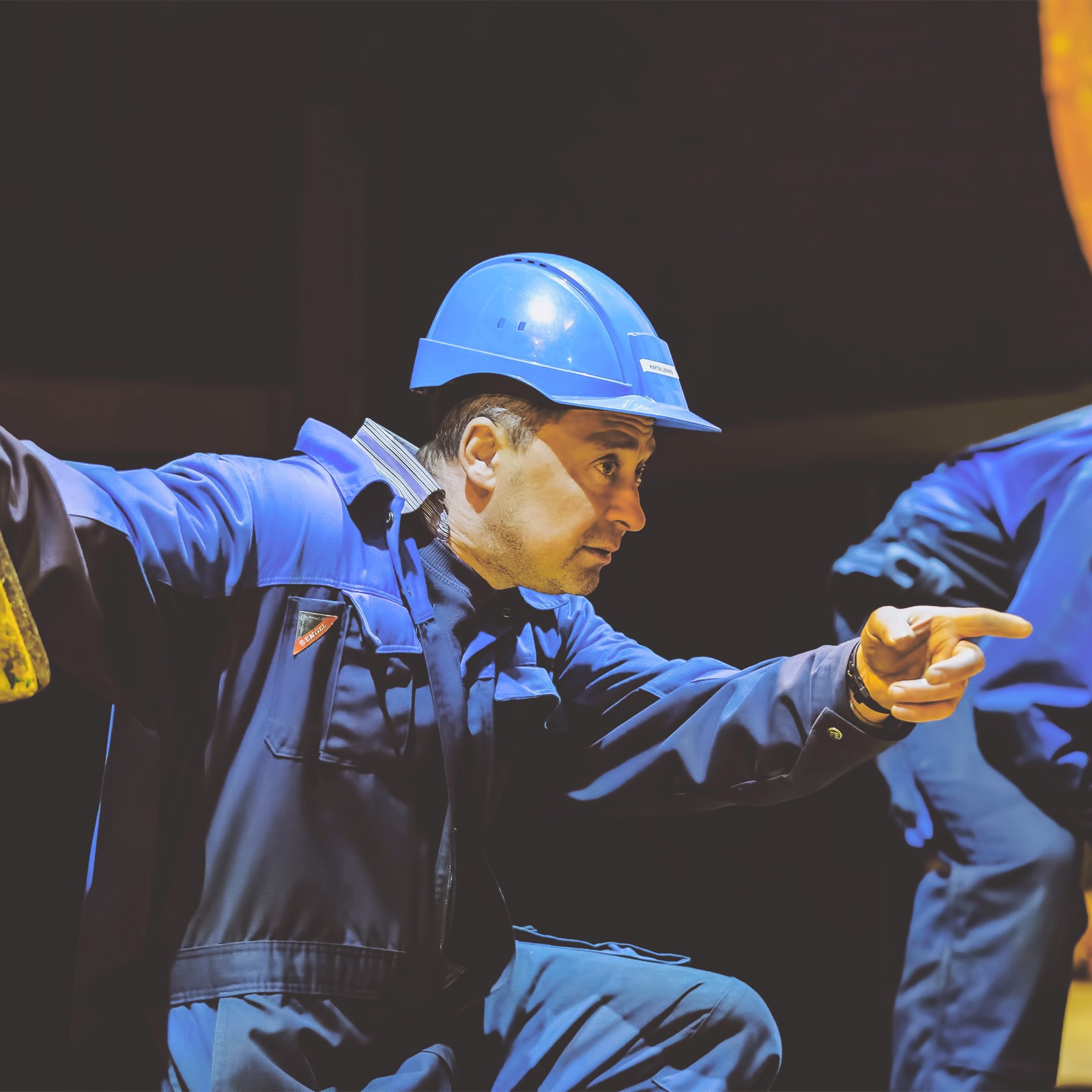 En gruppe indsutriarbejdere i blå keddeldragter på job