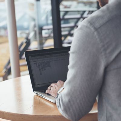 En mænd sidder med ryggen til og kigger på computer.