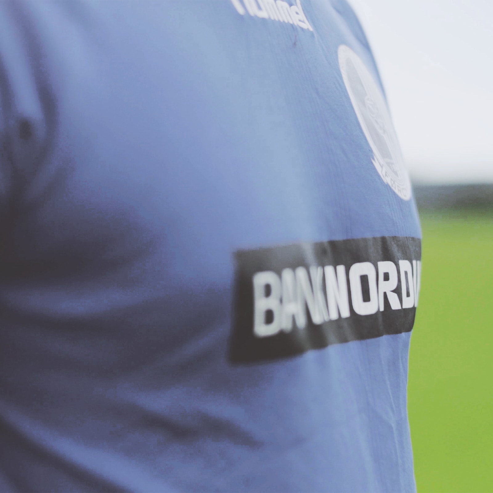 En fodboldspiller står på banen i sin trøje, der er sponsoreret af BankNordik