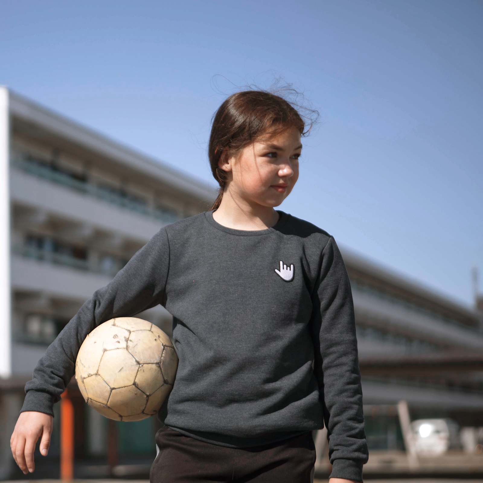 En sej pige står med sin fodbold