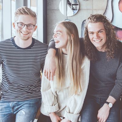 En gruppe unge sider sammen på en café og smiler