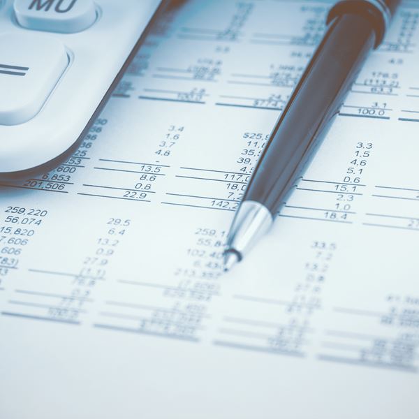 Et budget ligger på et bord sammen med en kuglepen og en lommeregner