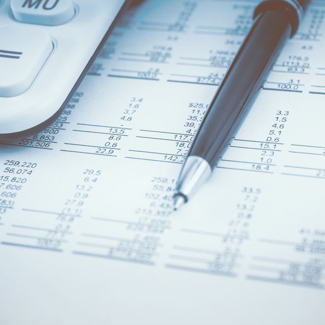 Et budget ligger på et bord sammen med en kuglepen og en lommeregner