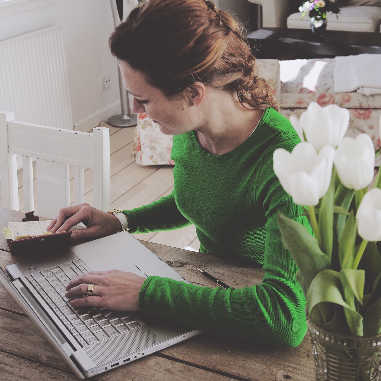 En rødhåret kvinde arbejder ved sin computer