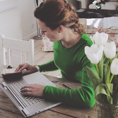 En rødhåret kvinde arbejder ved sin computer