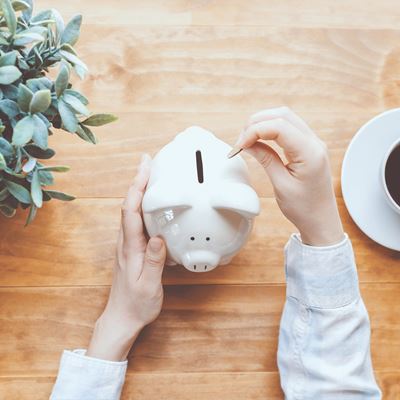 En mand fylder penge i en sparegris