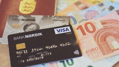 Et pas og et Banknordik betalingskort ligger ovenpå euro kontanter. 