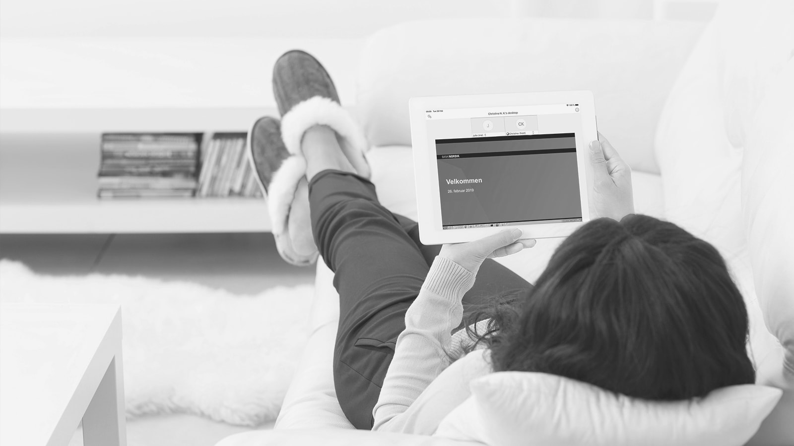 En kunde ligger på sofaen imens han holder møde med banken via sin computer.