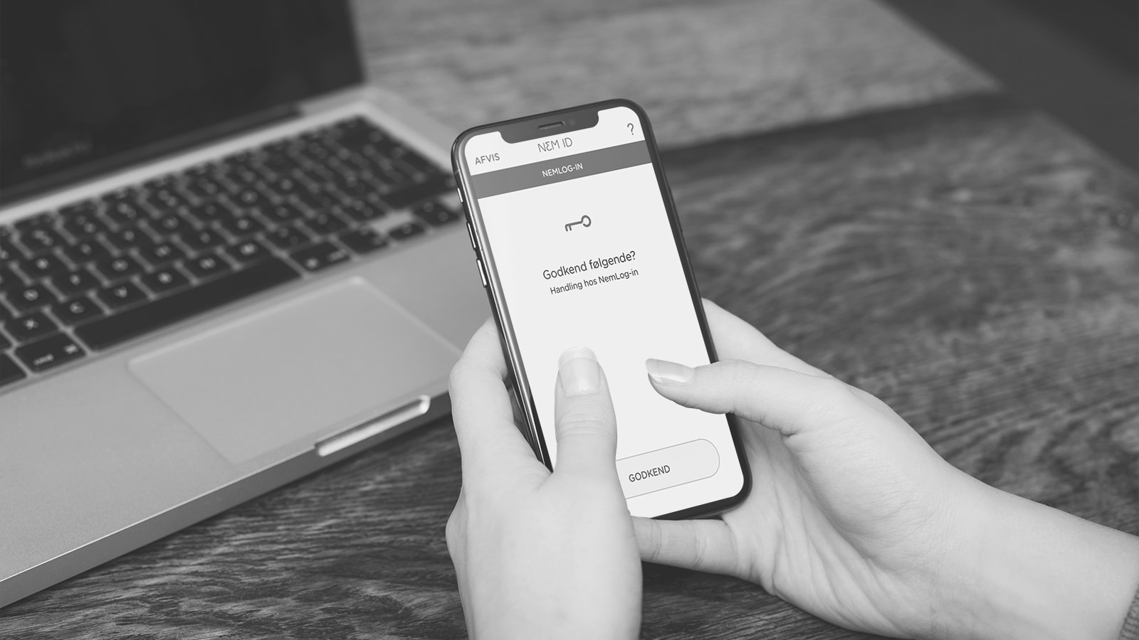 En smartphone skærm viser nøgleapp'en med en computer i baggrunden. 