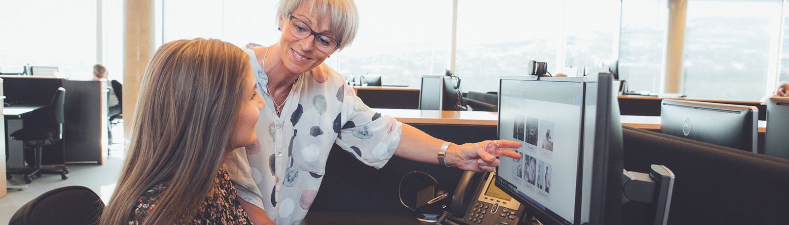 To kvinder kigger i computerskærm på kontor