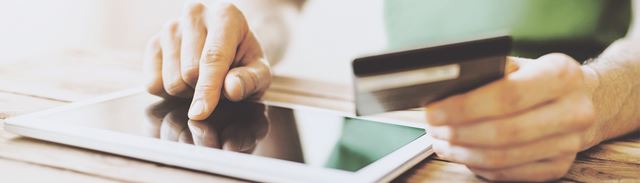 En mand betaler online på sin tablet med sit betalingskort