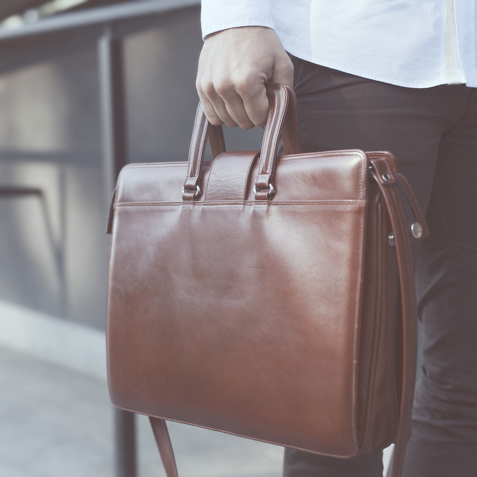 En mand i skjorte går med en attachemappe i hånden