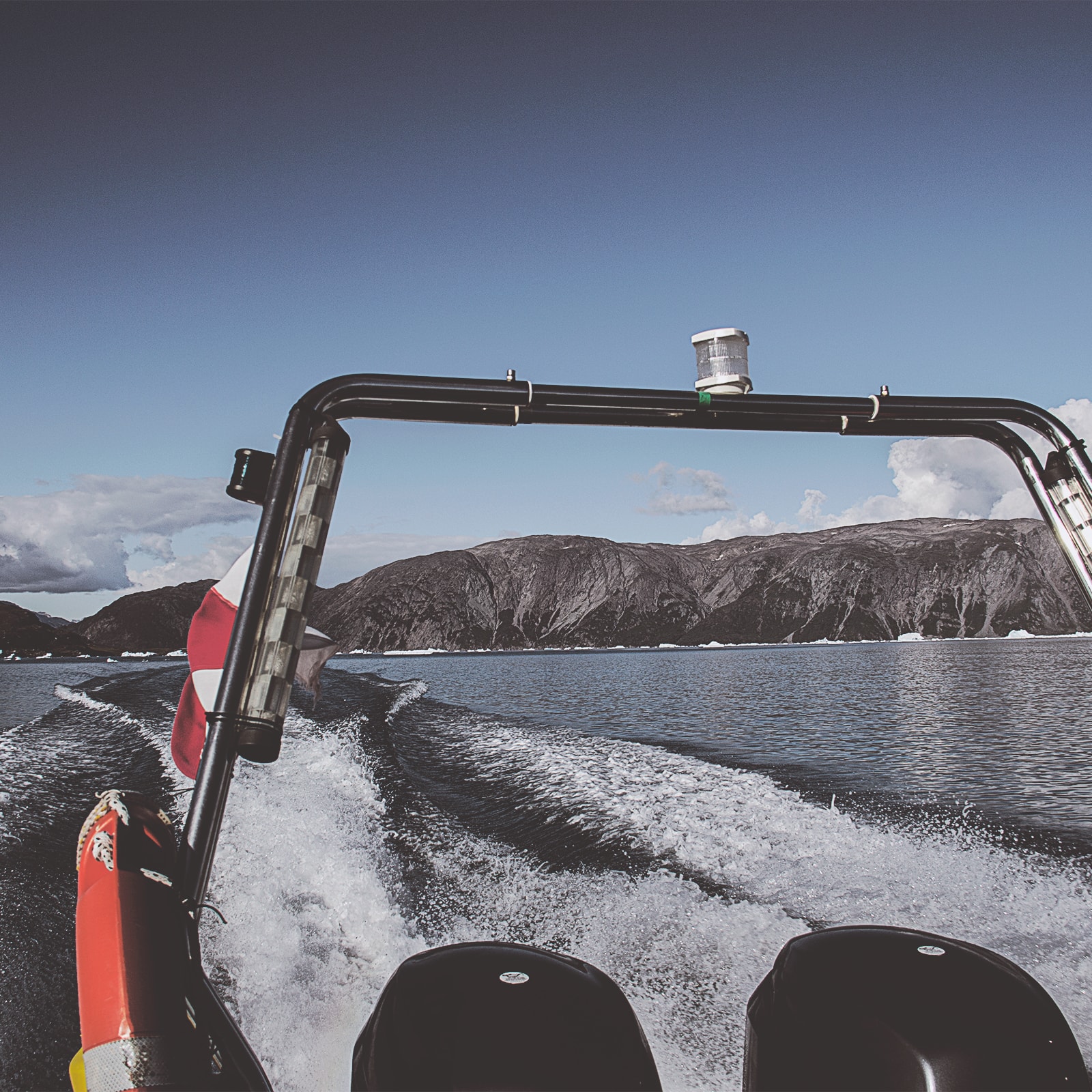 Speedbåd ligger ved vandet med udsigt over vand og bjerge. 