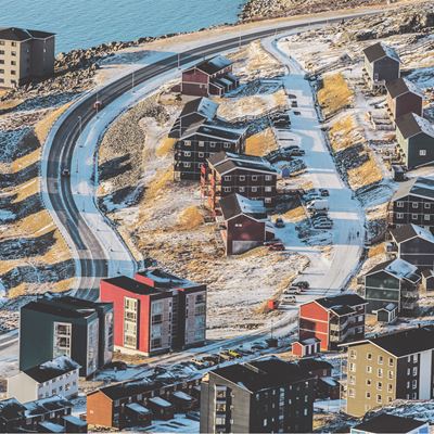 Udsigt over en grønlandsk bygd med veje beklædte i sne.