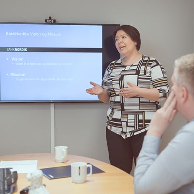 En kvinde holder en præsentation med en skærm i baggrunden.