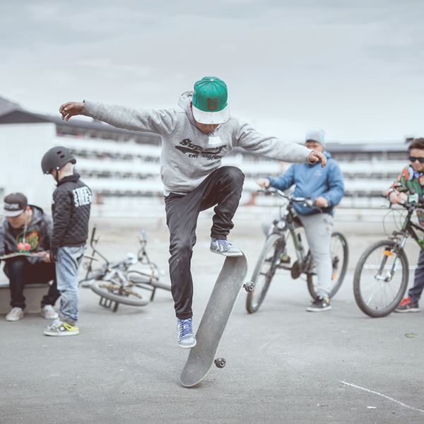 Unge drenge hænger ud på en sketarplads ned deres cykler og skateboard. 