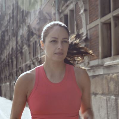 En kvinde i en rød trænings top, set forfra, løber en tur på gaderne i København.