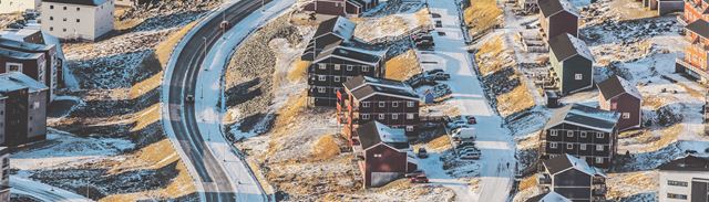 Udsigt over en grønlandsk bygd med veje beklædte i sne. 