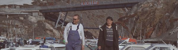 To arbejdsmænd går ved siden af hinanden i Ilulissat havn.